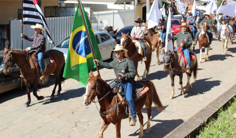 Homens cavalgando com as bandeiras do Brasil e de São Paulo no aniversário de Paraibuna