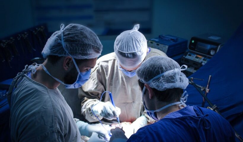 cirurgião e assistentes operando em uma mesa de cirurgia