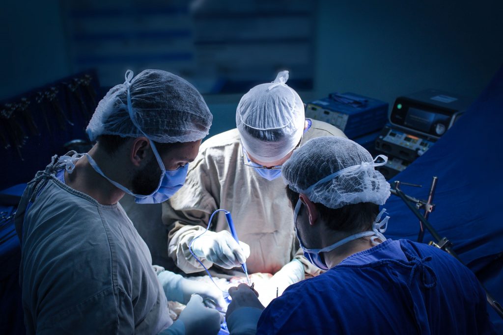 cirurgião e assistentes operando em uma mesa de cirurgia