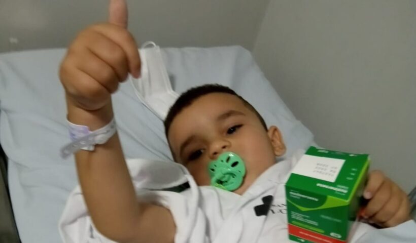 Menino deitado na cama segura caixa de remédio de alto custo em Lorena