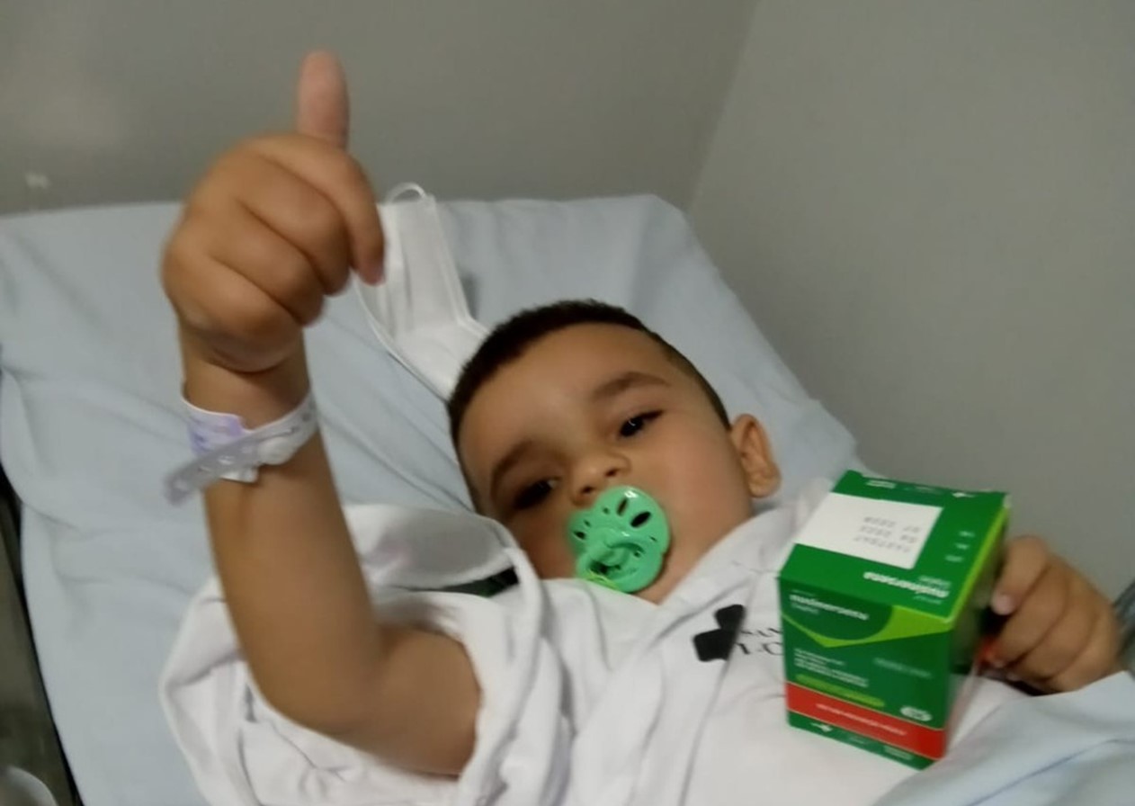 Menino deitado na cama segura caixa de remédio de alto custo em Lorena