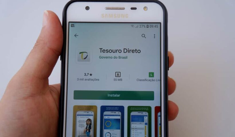 Mão segura celular que mostra Aplicativo do Tesouro Direto