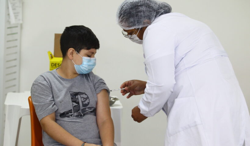 Adolescente sendo vacinado durante campanha de vacinação contra a covid-19 e a Influenza