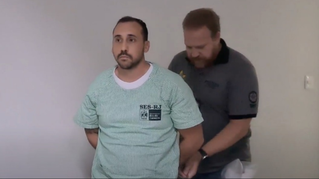 Anestesista acusado de estupro sendo algemado por policial. Ele terá 15 dias para prestar informações sobre sua conduta