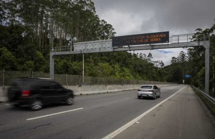 trecho da serra antiga da tamoios, com placa eletronica de avisos e ceu nublado.
