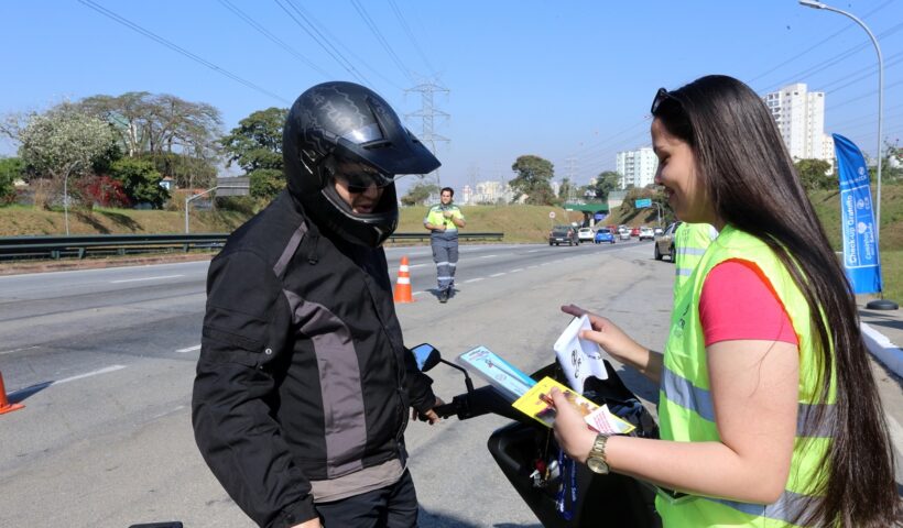 Motociclista sendo orientado por colaboradora da CCR RioSP que ofecere check-up aos profissionais que trabalham com moto