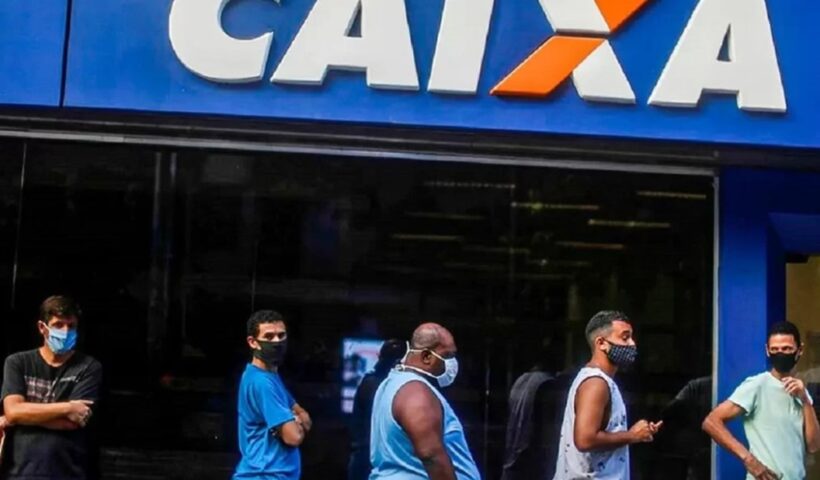 Pessoas com máscaras faciais na fila para entrar em agência da Caixa. Abono salarial será pago a 1,1 milhão de trabalhadores nesta segunda