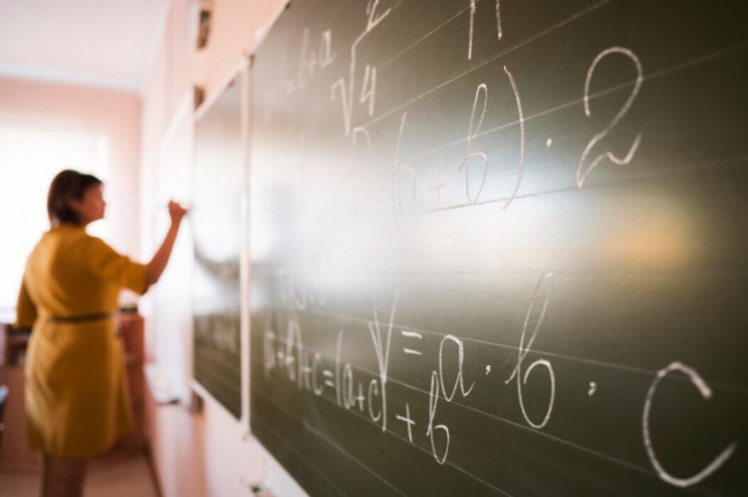 Professora escrevendo no quadro negro em escola. Governo de SP anunciou concurso para contratação de 15 mil professores