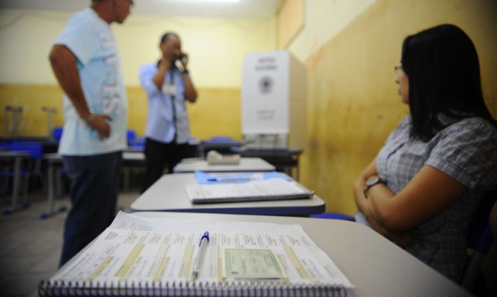 Foto de mesário olhando para eleitor. Eleição só acaba quando termina?