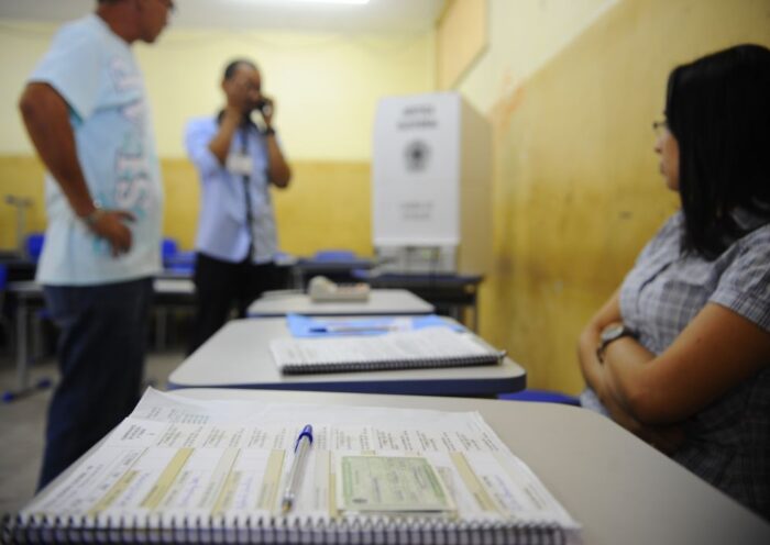 Foto de mesário olhando para eleitor. Eleição só acaba quando termina?