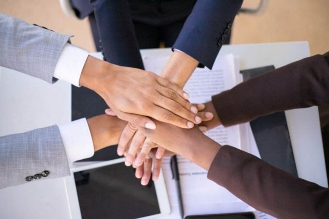 mãos unidas aocentro deuma mesa para enfatizar Relacionamento no mercado de trabalho