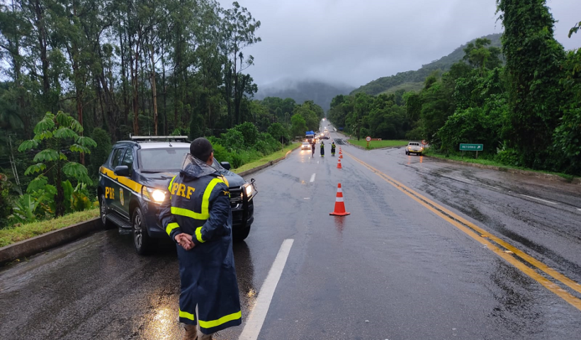 policial da PRF uniformizado, de pé, em frente a uma viatura da prf,. no trecho interditado da rodovia Rio-Santos por risco de deslizamento de terra