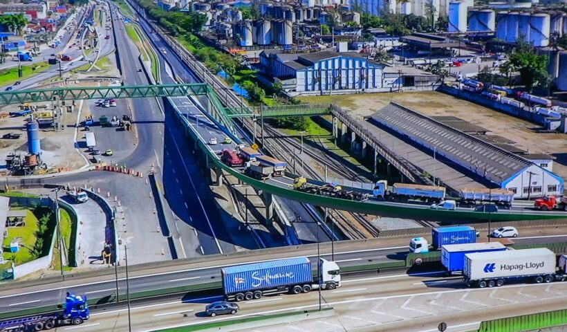 complexo viário da entrada de santos visto de cima, com carros prédios e caminhões