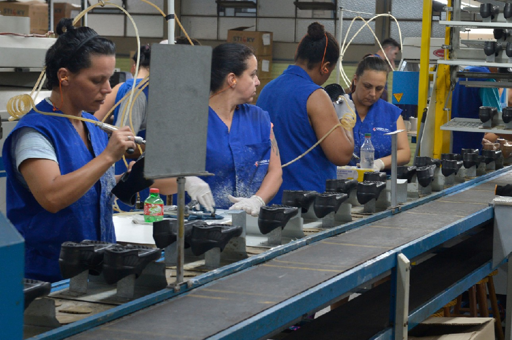 quatro mulheres de uniforme azul manuseiam maquinas numa industria. confianca no setor aumentou