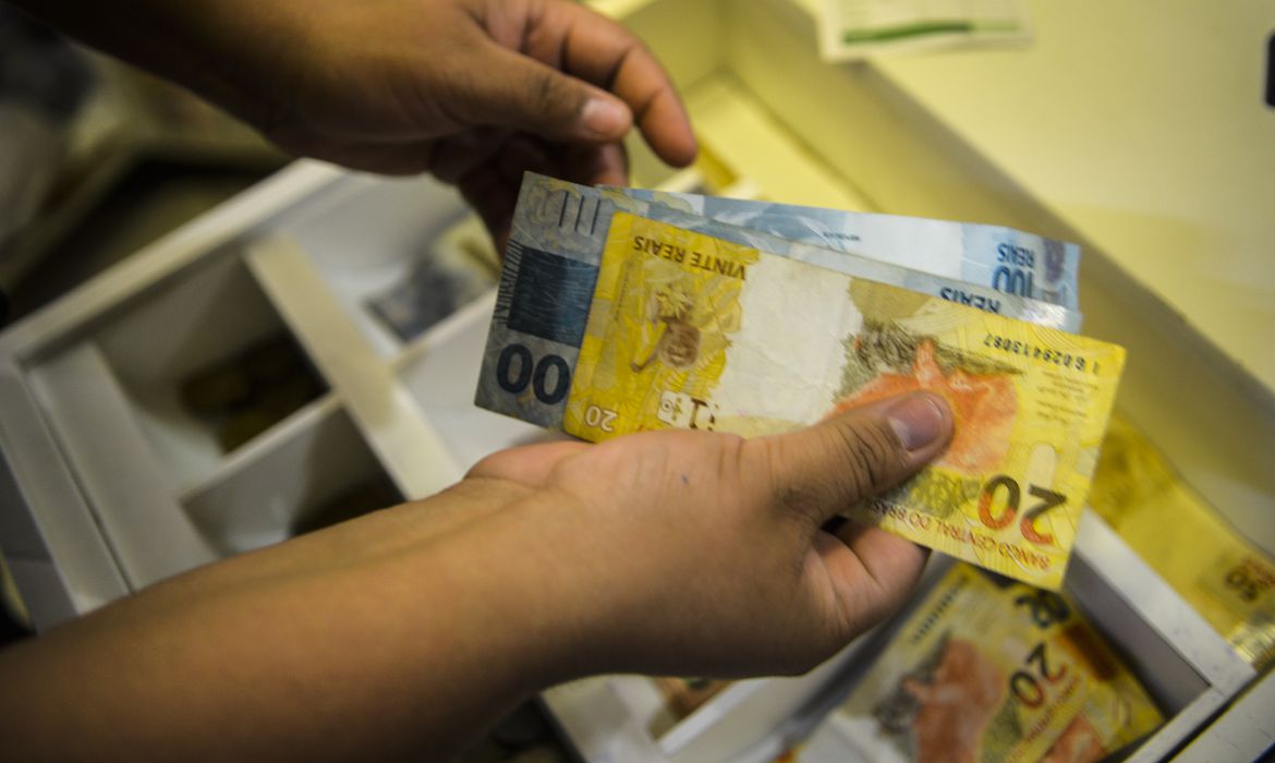 mãos com notas de dinheiro. Inflação oficial do país