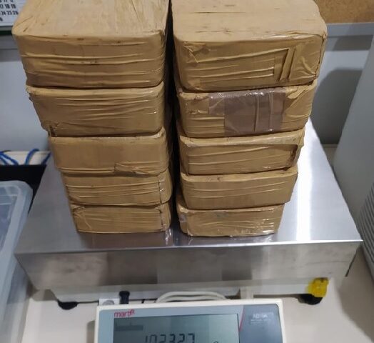 PRF prende passageira com 10kg de cocaína na Dutra; a droga está dividida em 10 tijolos embalados com adesivo marrom; o material está sobre uma balança de pesar