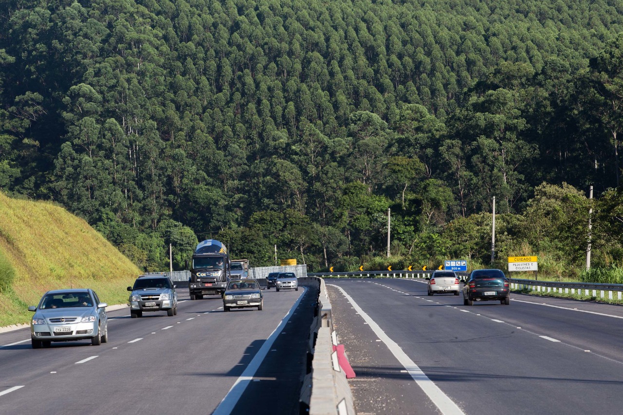 Rodovias do Litoral Norte esperam quase 300 mil veículos no Natal; imagem mostra trecho da rodovia dos tamoios com carros nos dois sentidos e serra do mar ao fundo