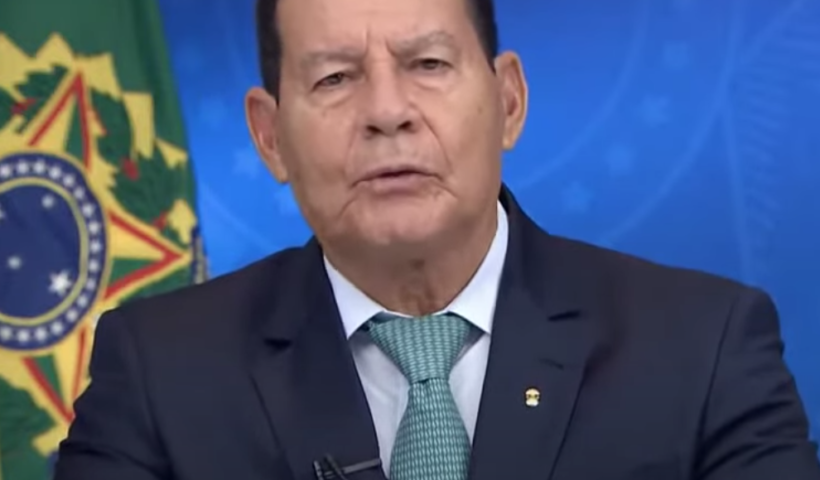 presidente em exercício hamilton mourao faz pronunciamento em rede nacional; ele veste camisa branca, terno azul marinho e gravata azul clara, bandeira do brasil ao fundo