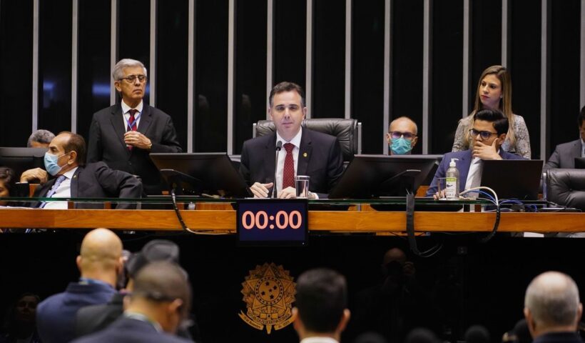 presidente da camara dos deputados sentado à mesa do congresso, com outros dois parlamentares ao fundo. congresso aprova regras para orcamento secreto