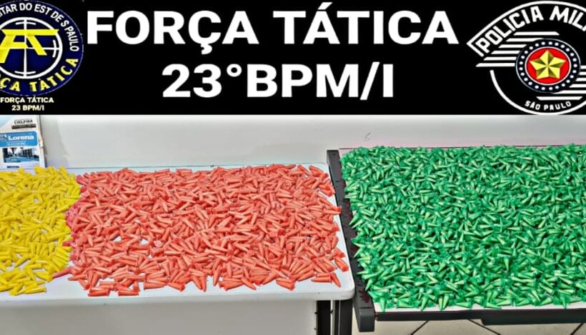 drogas apreendidas sobre mesa da polícia militar; há pinos de cocaína coloridos de amarelo, vermelho e verde; droga armazenada em sacos de ração