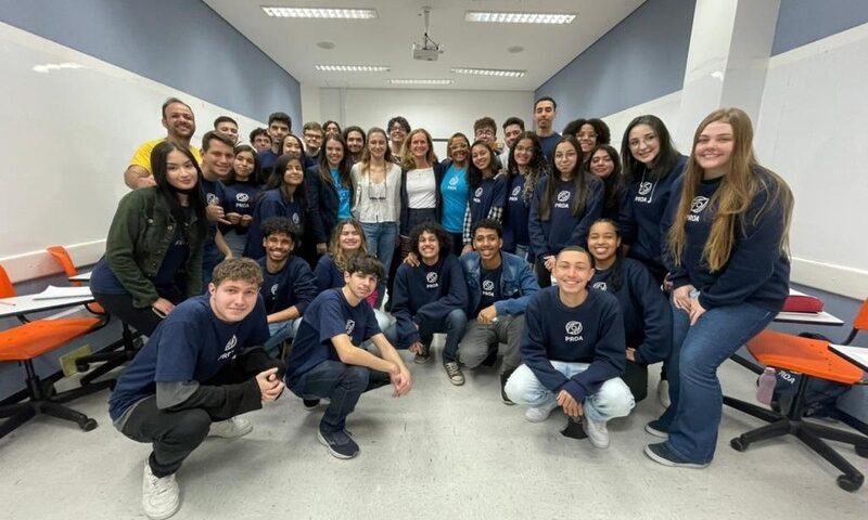 dezenas de alunos do instituto proa com uniforme azul marinho, sorrindo para a câmera. curso profissionalizante grátis