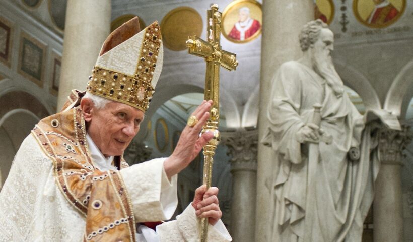 papa bento xvi sorri com mao levantada, segurando cruz, em missa durante seu pontificado