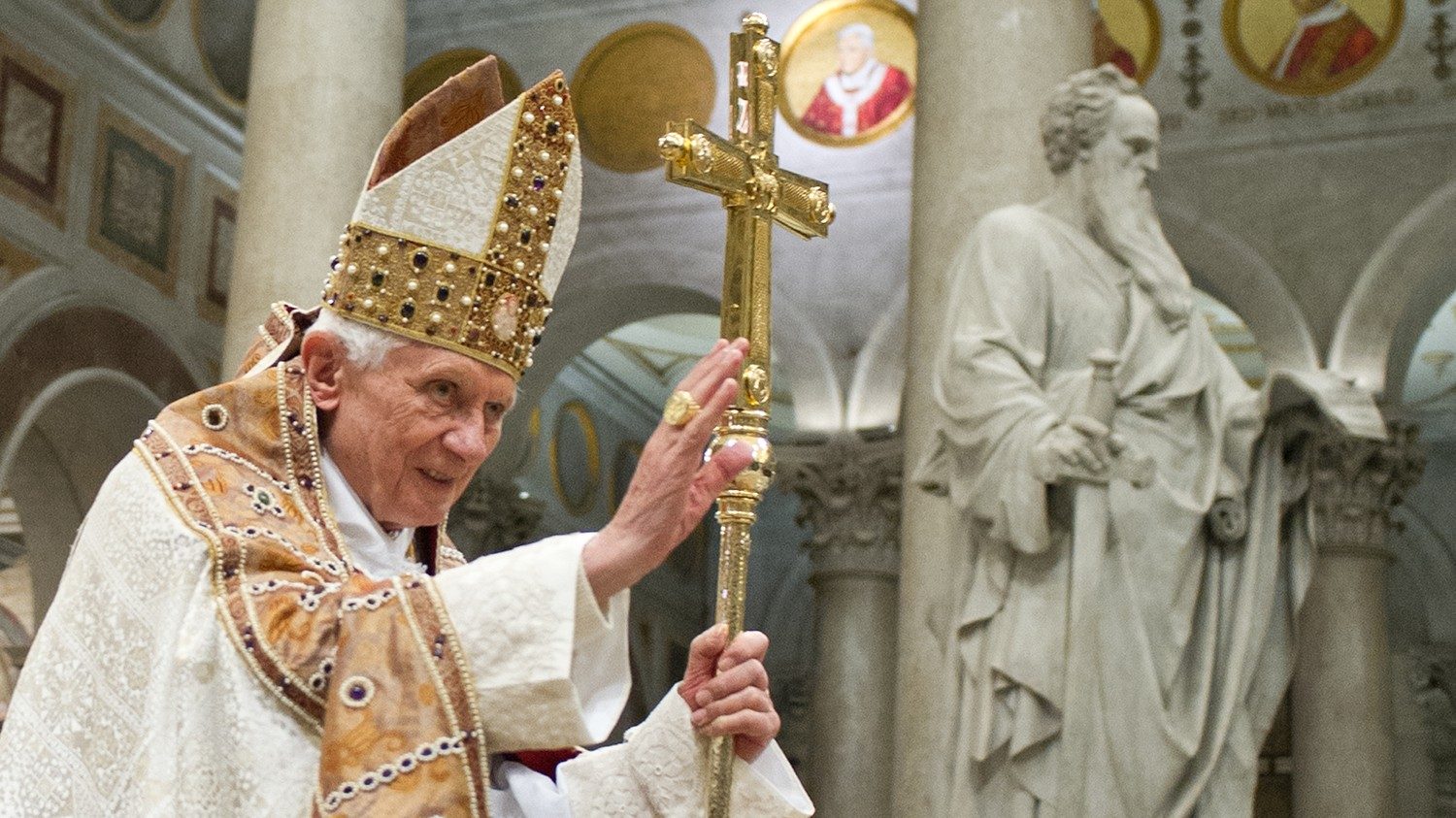 papa bento xvi sorri com mao levantada, segurando cruz, em missa durante seu pontificado