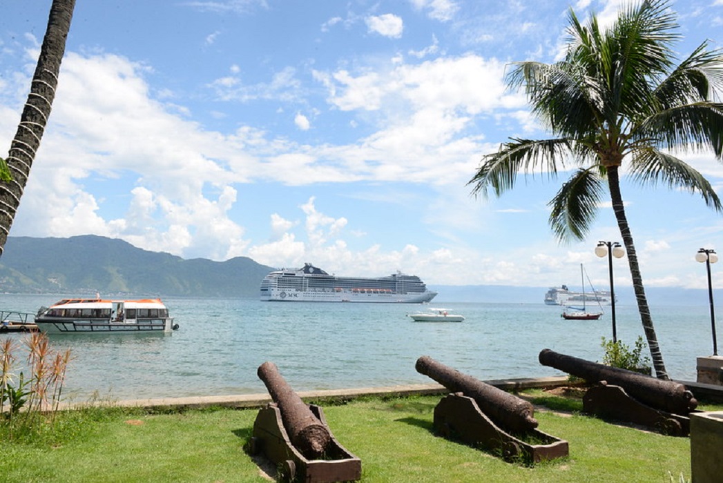 ilhabela, que reivindica total dos royalties do petroleo explorado na regiao, aparece na imagem com mar azul, navios e três canhões no solo, apontados para o mar.