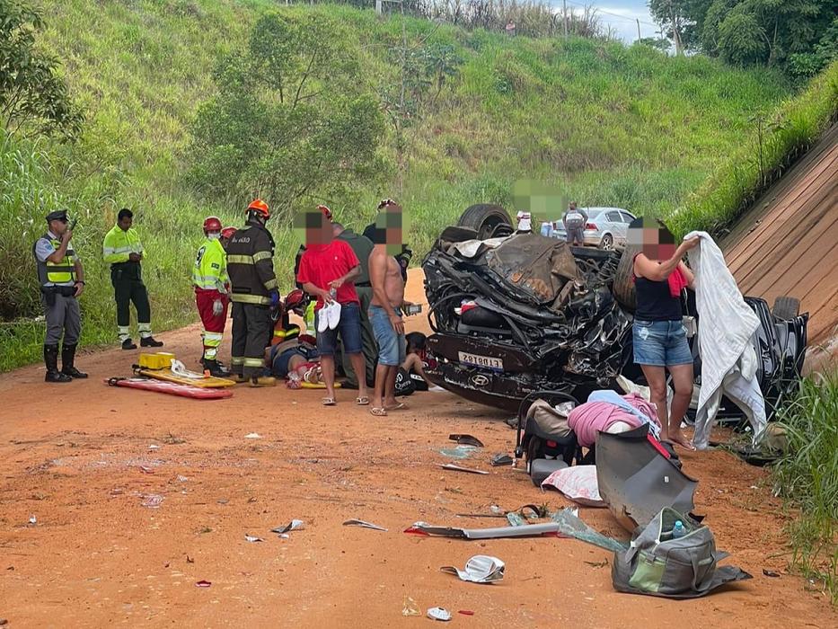 carro capotado e em destroços, há pessoas em volta, morro com gramado verde ao funo; bebe de tres meses está entre feridos