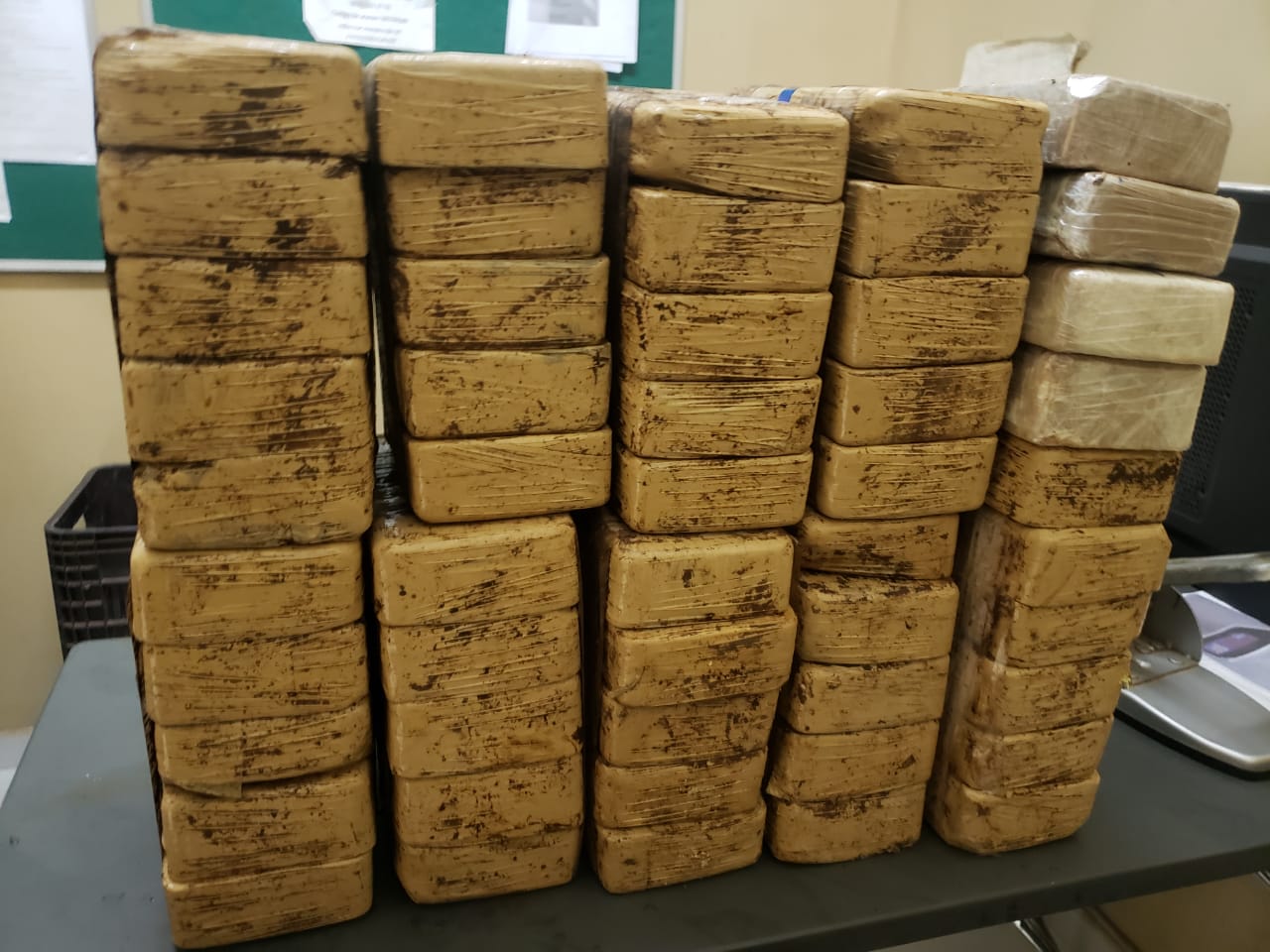 dezenas de tijolos com cocaína, embrulhados em plástico cor de mostarda e empilhados sobre a mesa da policia; Caminhonete com 50 kg de cocaína foge da PRF sentido Santuário de Aparecida