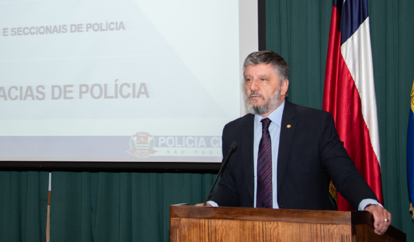 Waldir Antônio Covino Jr., vestido de terno e gravata, fala ao microfone, sobre palco, sobre polícia civil em SP