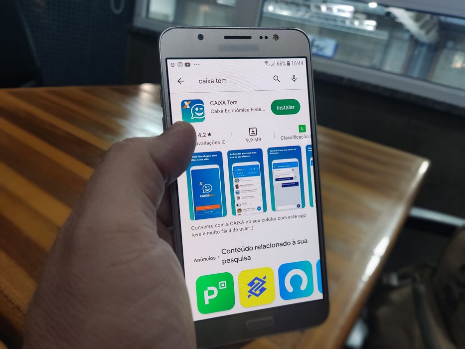 Mão segurando celular acessando dados do Pis. Abono salarial_valores podem ser consultados a partir deste domingo