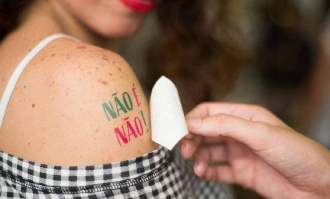 Mulher com adesivo no braço com a frase: Não é não. Tarcísio de Freitas sanciona lei que obriga bares e boates no auxílio a mulheres em situação de risco
