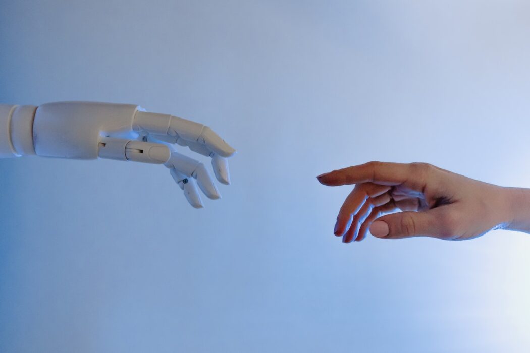 Mão robótica próxima de tocar em mão humana. CBN Inovação: Inteligência Artificial já chegou no mundo prático