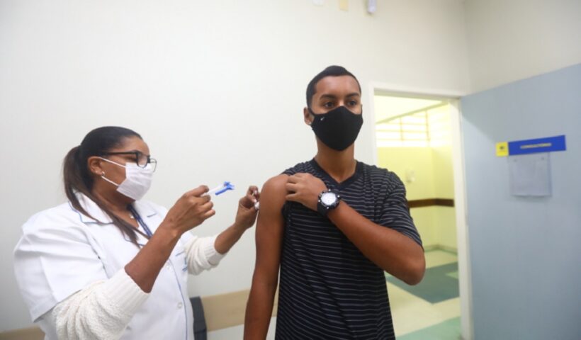 Jovem sendo vacinado por agente de saúde de sjc. Vacinação contra a gripe segue até o final de julho