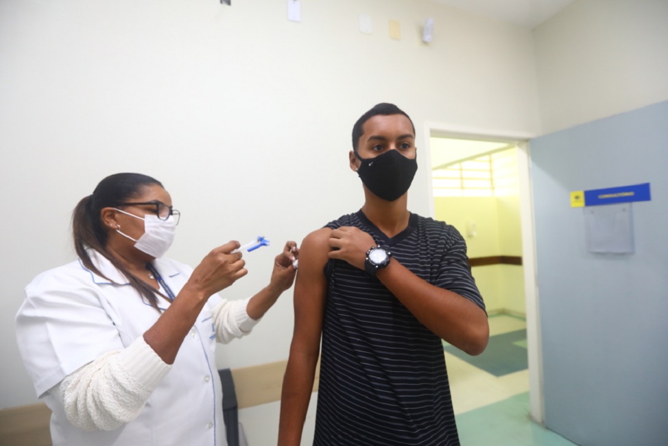 Jovem sendo vacinado por agente de saúde de sjc. Vacinação contra a gripe segue até o final de julho
