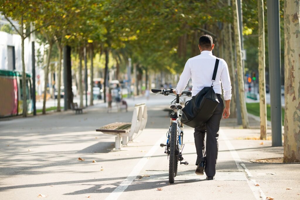 Homem de costas, vestindo roupa social, caminhando em ciclovia com sua bicicleta. Entrou em vigor nesta segunda (03/07/23) novas regras para bicicletas elétricas e ciclomotores