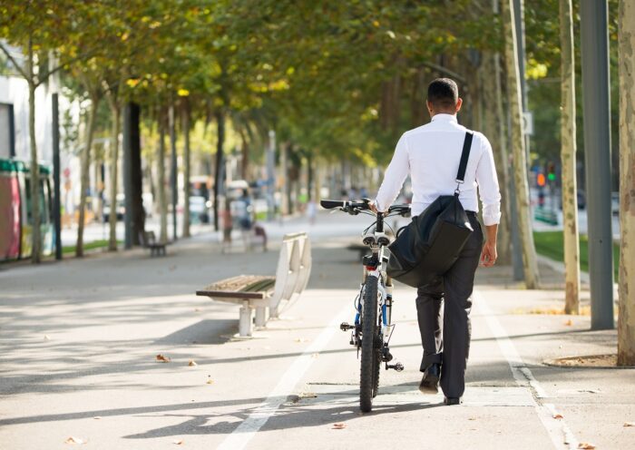 Homem de costas, vestindo roupa social, caminhando em ciclovia com sua bicicleta. Entrou em vigor nesta segunda (03/07/23) novas regras para bicicletas elétricas e ciclomotores