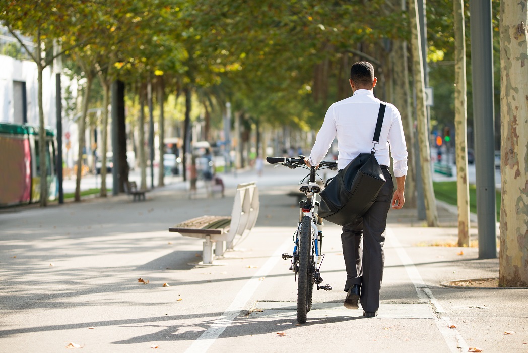 Homem de costas, vestindo roupa social, caminhando em ciclovia com sua bicicleta. Entrou em vigor nesta segunda (03/07/23) novas regras para bicicletas elétricas e ciclomotores