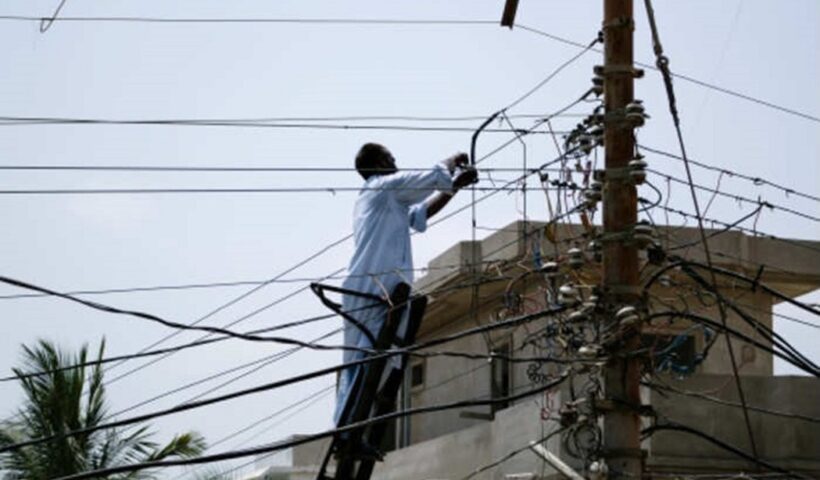 Homem em escada no poste de luz em ato de furto de energia/fraudes com ebergia