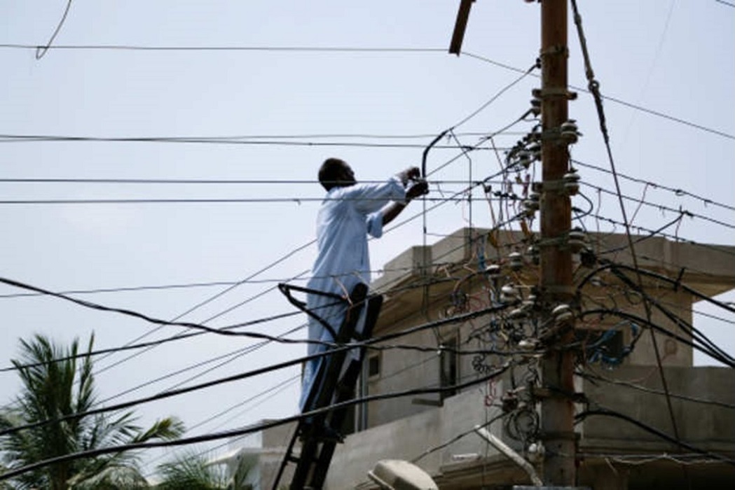 Homem em escada no poste de luz em ato de furto de energia/fraudes com ebergia