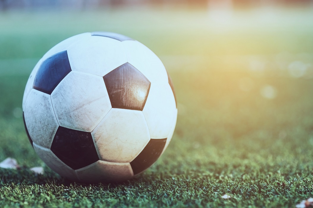 Bola de futebol sobre um gramado de campo. Apostas esportivas é o tema da matéria