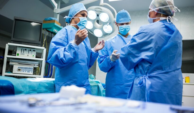 Cirurgiões e enfermeiros interagindo entre si na sala de operação do hospital. SP inicia repasses para o pagamento do novo piso da enfermagem