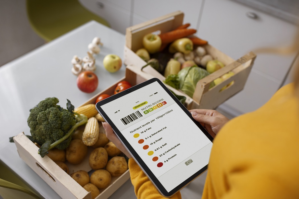 Pessoa segurando tablet com informações sobre nutrientes de produtos e sobre uma mesa, legumes e hortaliças. Alimentos customizados
