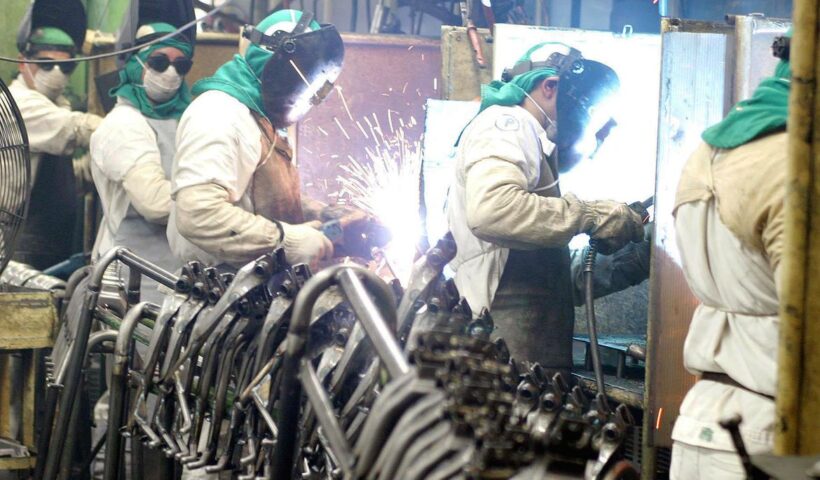 Funcionários de metalúrgica utilizando equipamentos de segurança em processo de soldagem em indústria. Mercado eleva para 2,56% projeção do crescimento da economia em 2023
