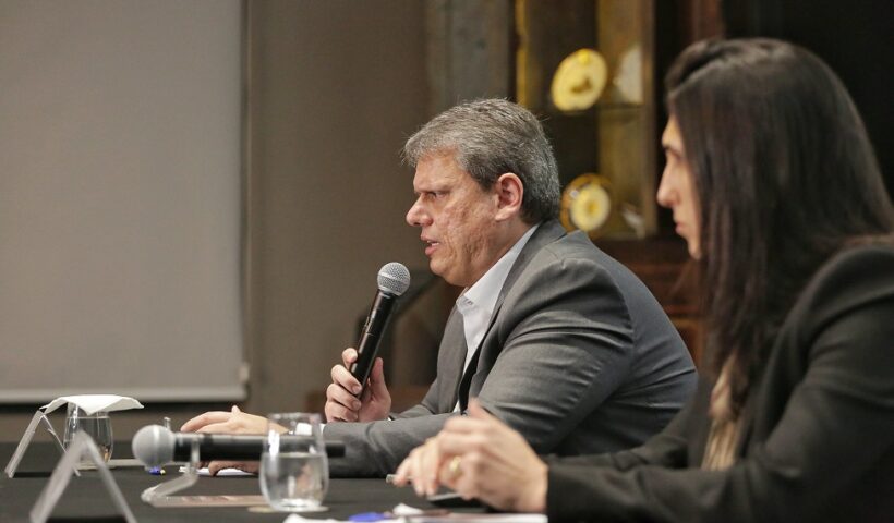 Governador Tarcísio de Freitas sentado junto á uma mesa em entrevista coletiva com repórteres. Pauta: Privatização da Sabesp