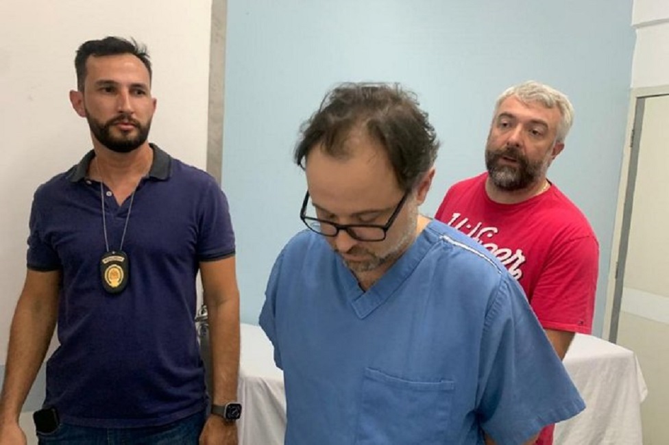 médico cirurgião João Batista do Couto Neto sendo preso pela polícia, acusado de causar 42 mortes