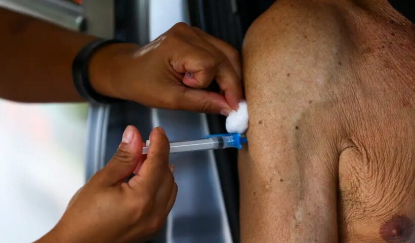 Mão de enfermeira vacinando braço de homem idoso. Registro de vacina contra bronquiolite é aprovado pela Anvisa