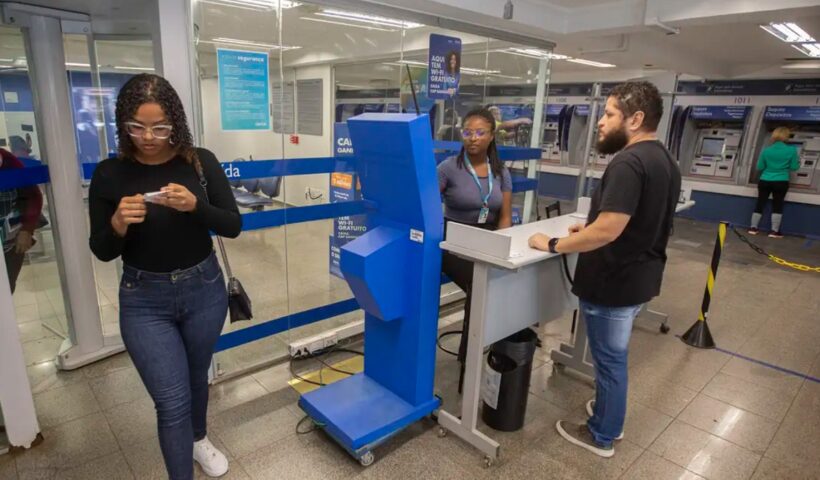 Clientes e funcionários dentro de agência da Caixa. Programa Desenrola é prorrogado por três meses