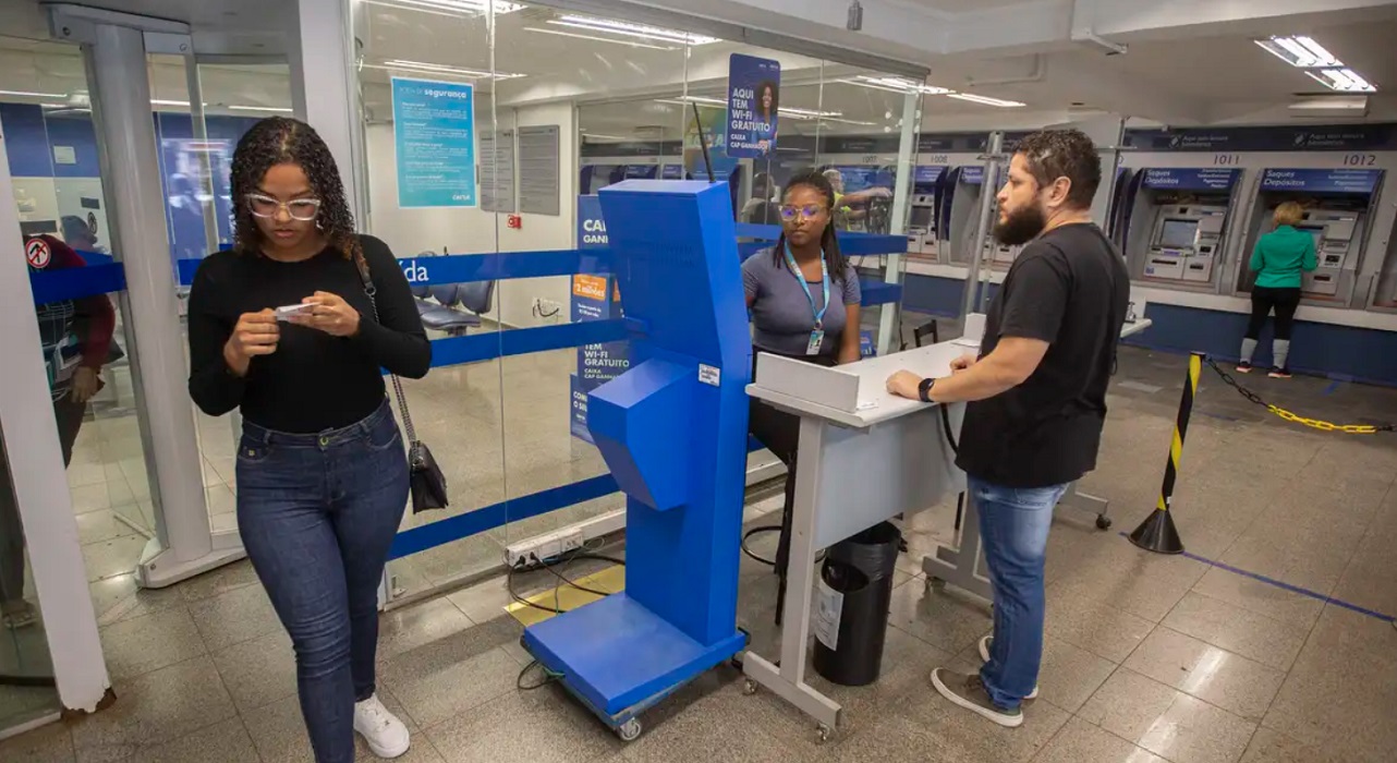 Clientes e funcionários dentro de agência da Caixa. Programa Desenrola é prorrogado por três meses